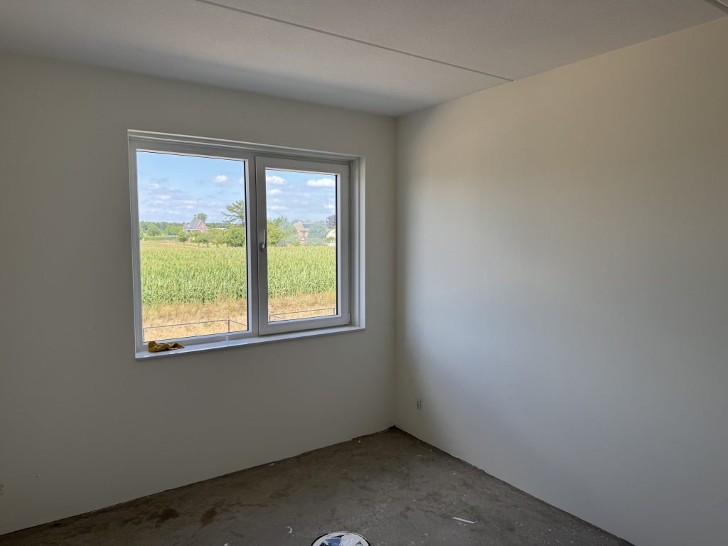 Lege kamer met lichte, gladde wanden en daglicht dat door het raam naar binnen valt